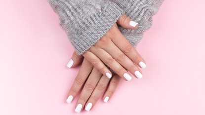 Woman with nails painted white on a pink backdrop