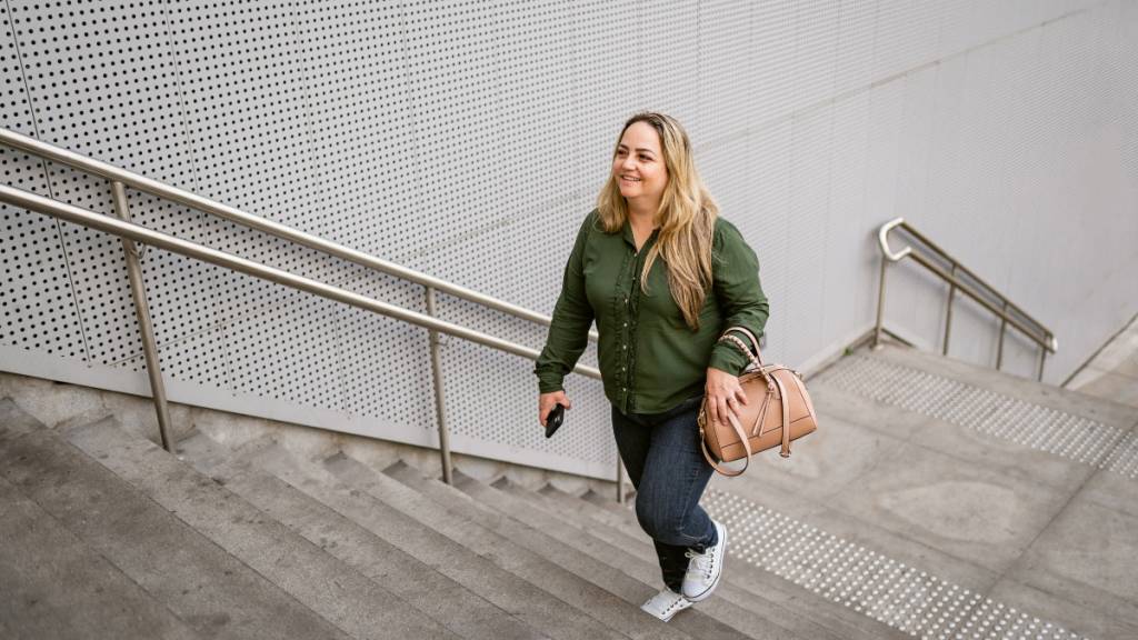 middle-aged woman happily climbs steps outdoors