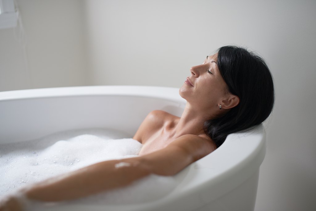 Woman taking a bath, which is one of the ways to use peppermint oil for skin