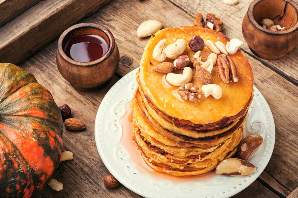 stack of gingerbread pancakes with maple syrup and nuts