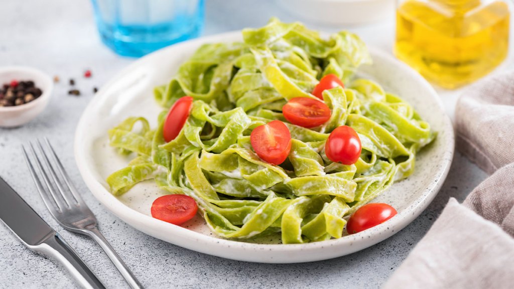 Plate of bean-based pasta topped with a hummus pesto sauce