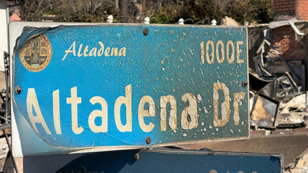 An overhead pole camera image shows wildfire damage to an Altadena Drive street sign and home destroyed by the Eaton Fire in Altadena, Los Angeles County, California on January 14, 2025. Powerful winds on January 14 threatened to rekindle and whip up major fires that have devastated parts of Los Angeles, killing at last 24 people and changing the face of America's second biggest city -- perhaps forever