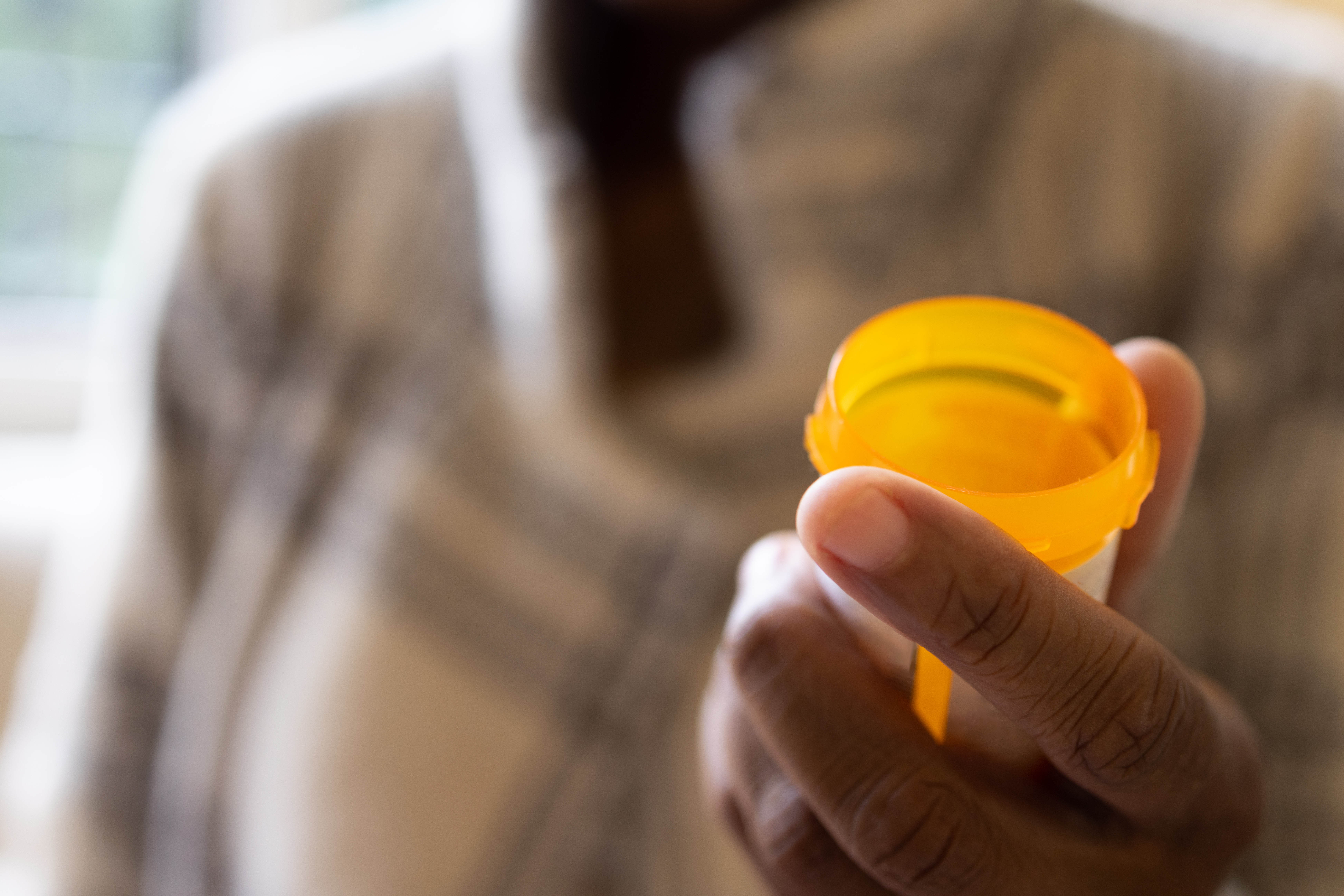 A person holding a pill bottle containing semaglutide pills.