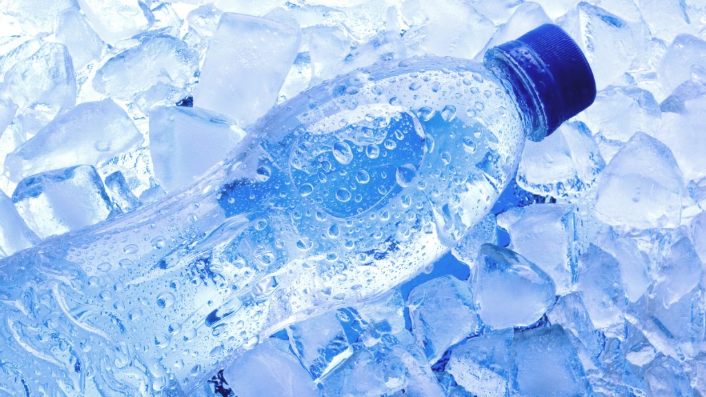 A bottle of water sitting in ice cubes