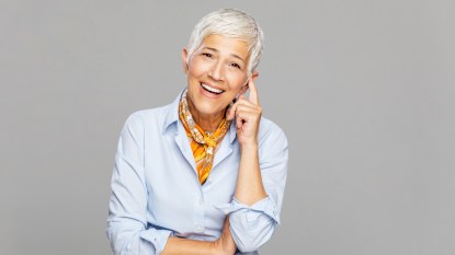 A woman with short grey hair and a blue shirt pointing to ear, which has a crackling sound