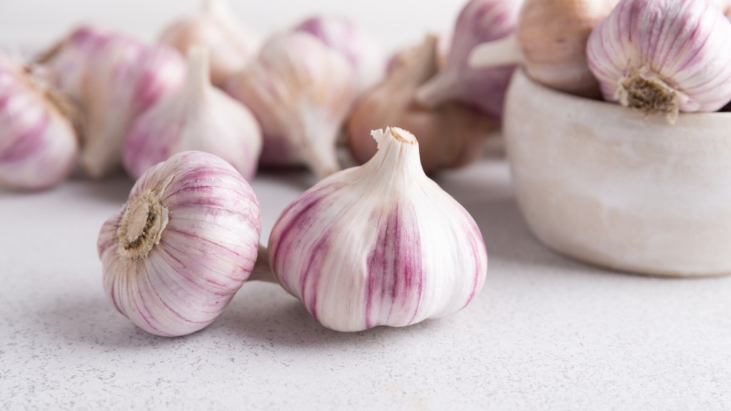 Cloves of fresh garlic, which have benefits when paired with honey, on a white countertop