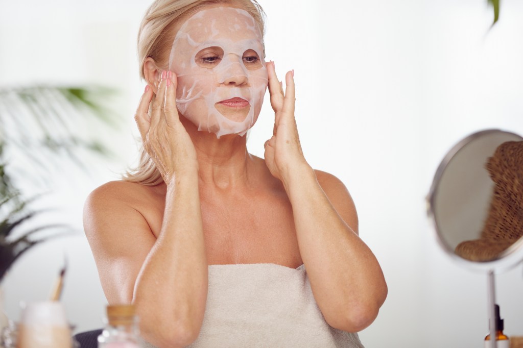 Mature woman applying face mask on skin