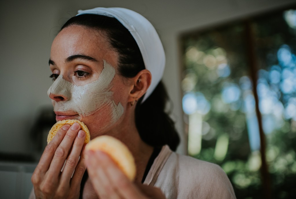 mature woman removing face mask with sponge