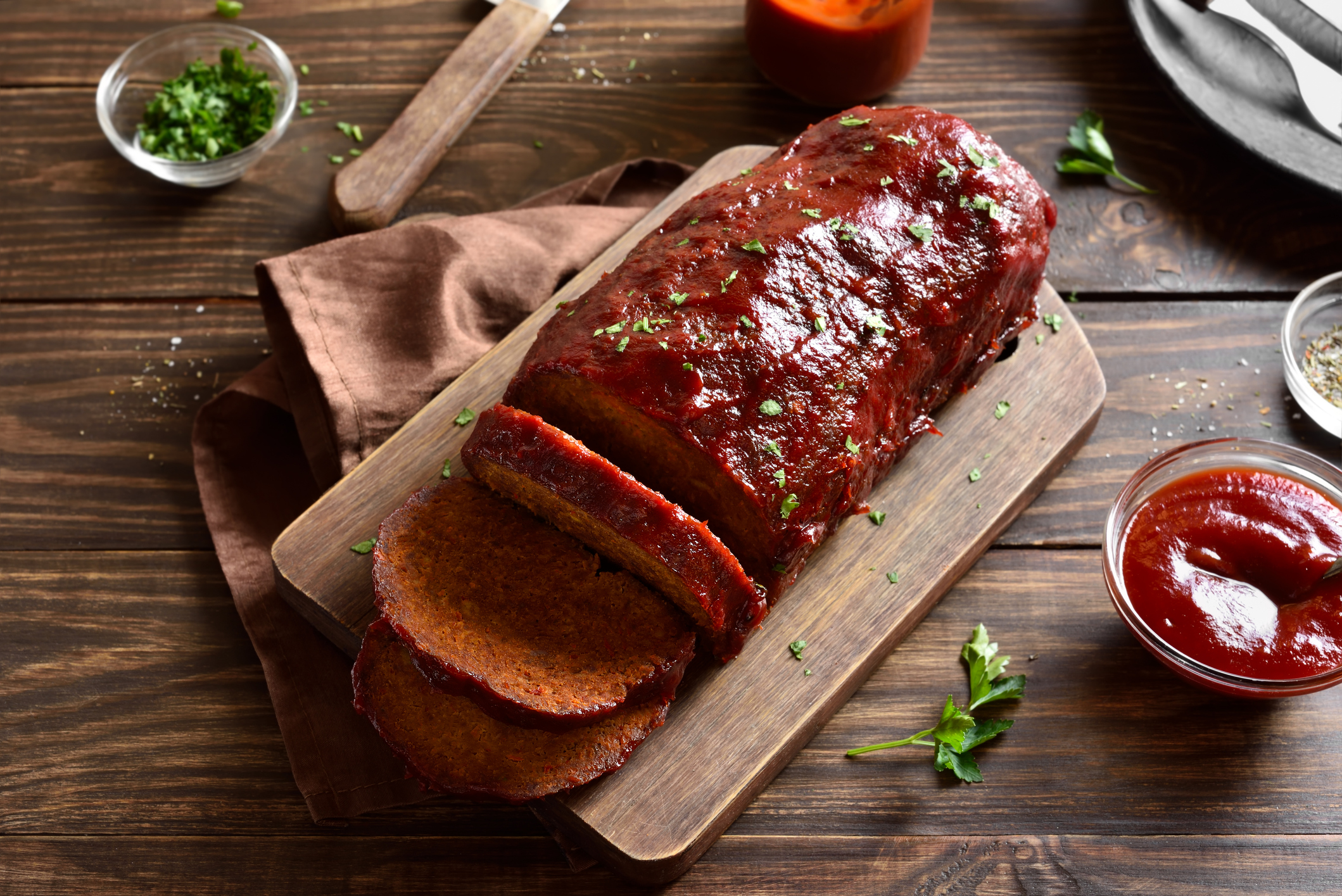 Ina Garten's meatloaf on cutting board, sliced with ketchup glaze