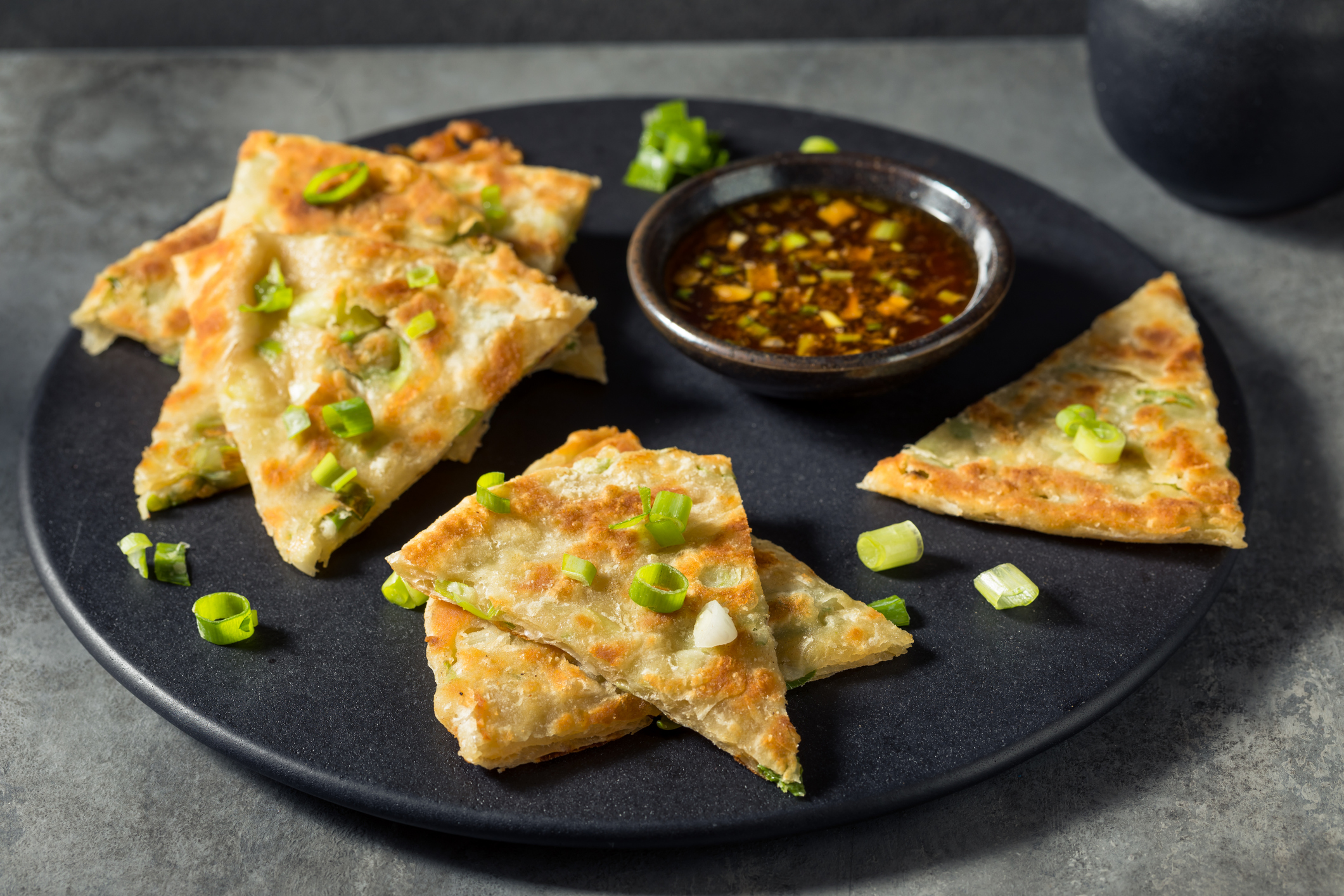 homemade Chinese scallion pancakes, cut on plate with dipping sauce