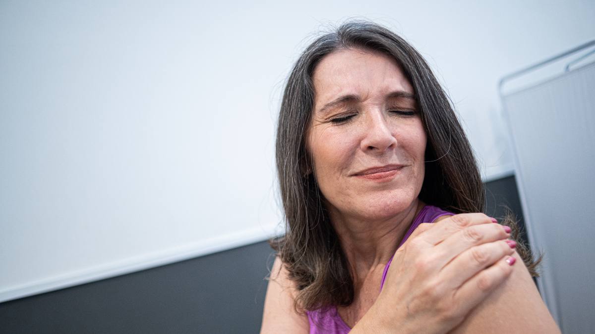 Woman gripping her frozen shoulder in pain
