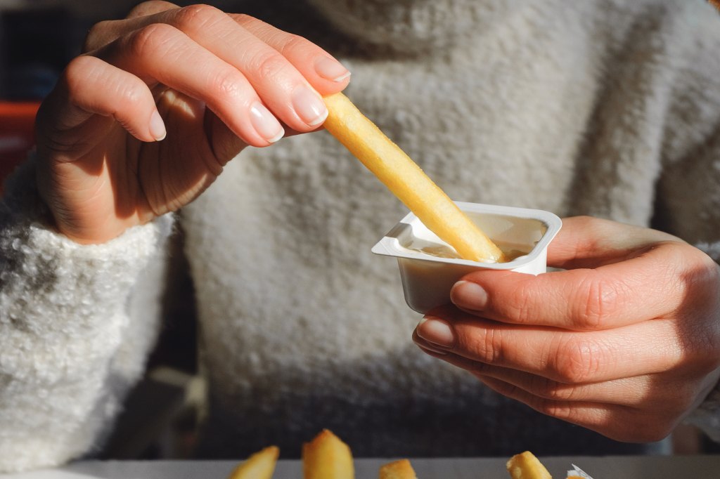 woman holding new garlic steak fries with garlic dipping sauce from Taco Bell new menu