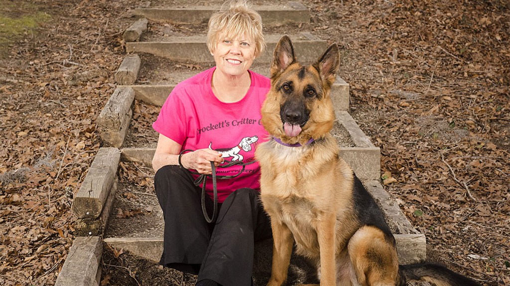 Image of Jeanne Crockett, who makes money with jobs working with animals, sitting outside with a German Shepherd