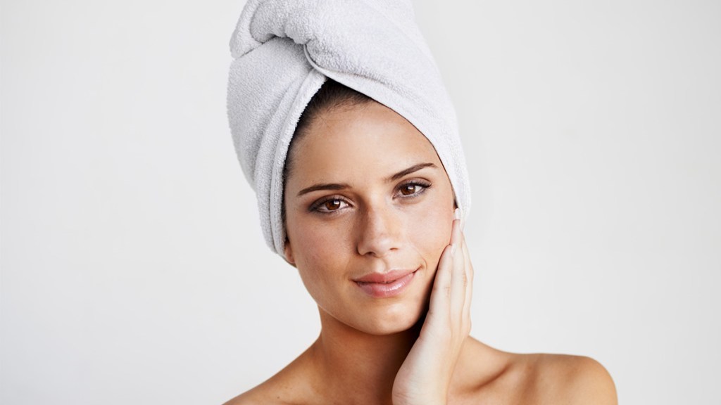 Woman with hair wrapped in a towel who is air drying her hair after learning how to air dry hair
