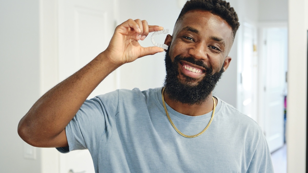 Young man holding up a set of Smileie aligners.