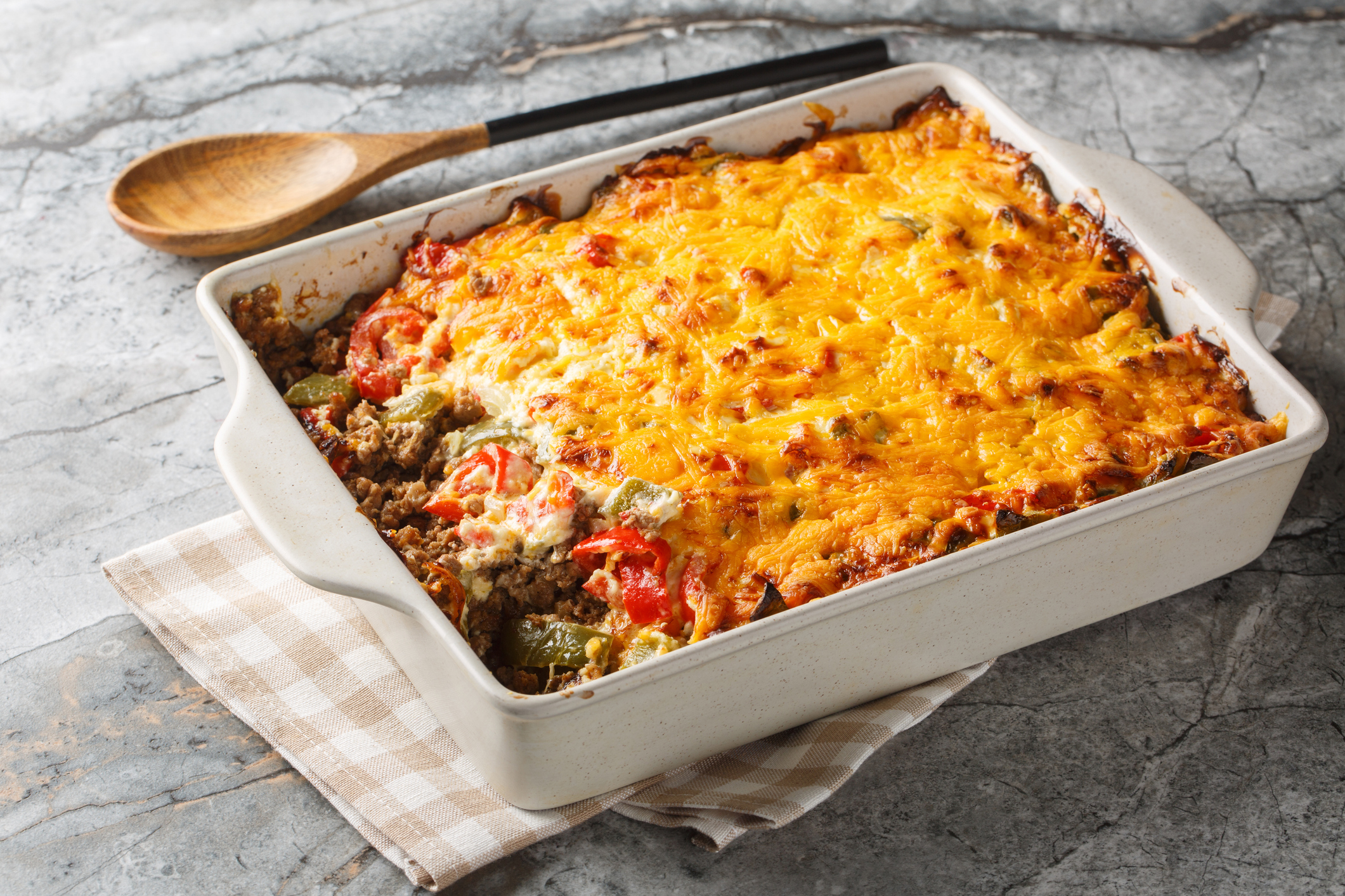 taco casserole with taco meat, vegetables, chips and a cheesy topping closeup on the baking dish on the table