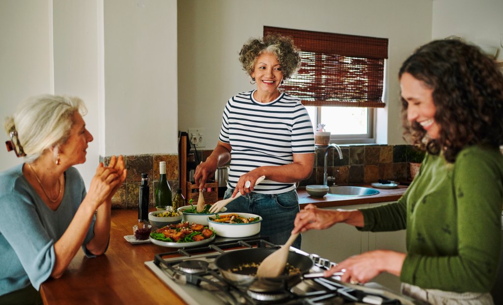 mature women in dementia preventing sundowning episode by cooking in kitchen together