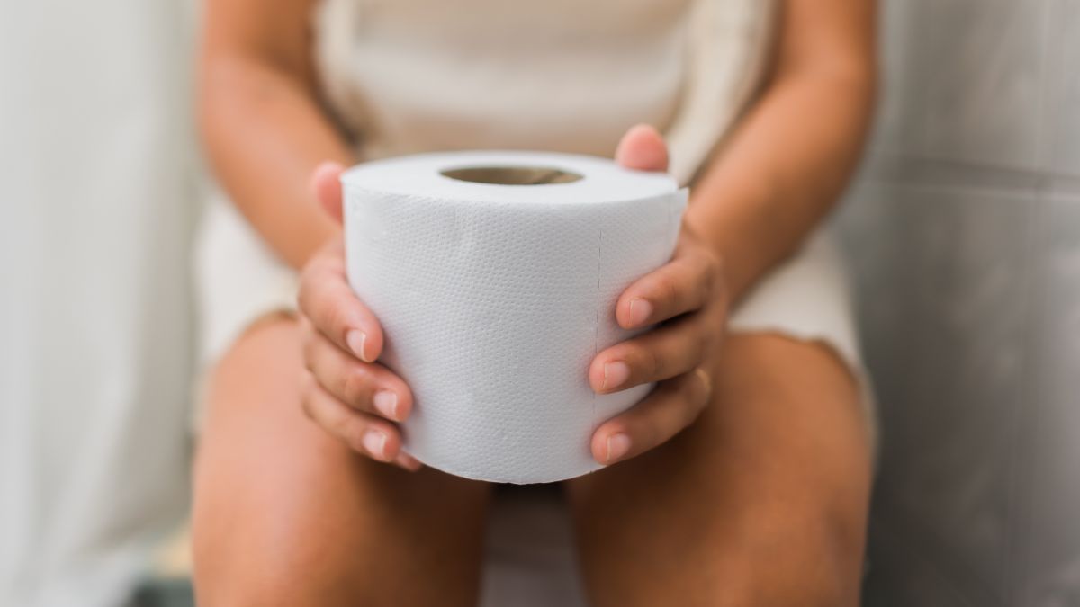 woman sitting on toilet holding toilet paper wondering why am I peeing so much all of a sudden