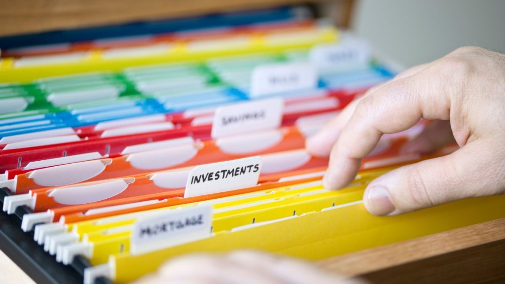 Hands searching through file folders with personal finance documents