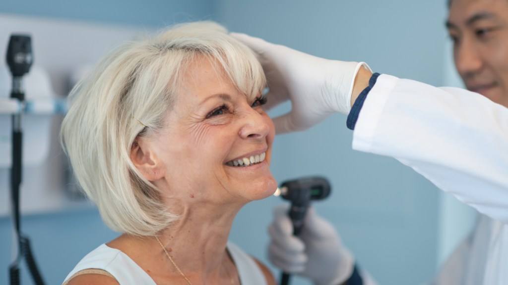 A mature woman getting hear dark ear wax examined by a doctor in a medical office