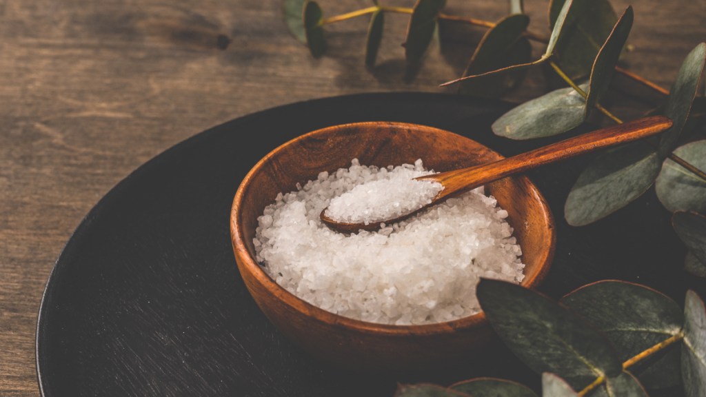 A wooden bowl of Epsom salts, which help with kneed pain when bending, beside eucalyptus leaves