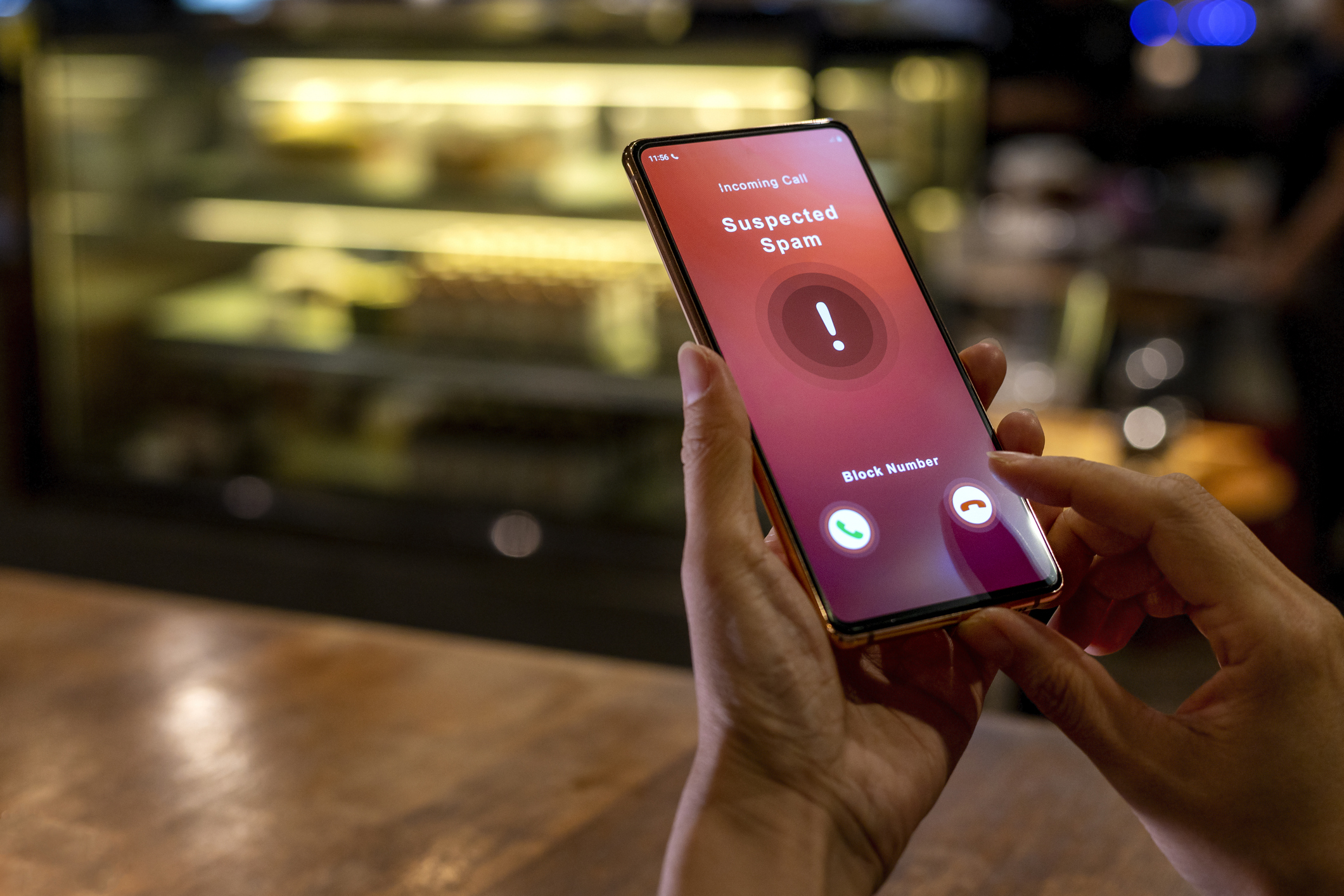 A woman receiving an incoming suspected spam call on her phone. The network provider detect the scam and show warning sign, woman rejects the call.
