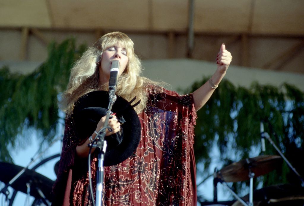 Stevie Nicks performing on stage wearing patterned, burgundy kimono