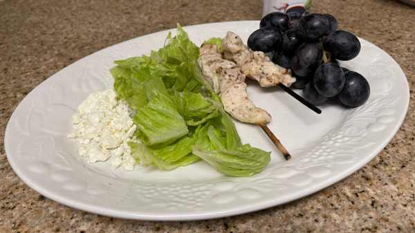 grilled chicken, romaine lettuce, concord grapes, feta cheese and balsamic dressing on a white plate