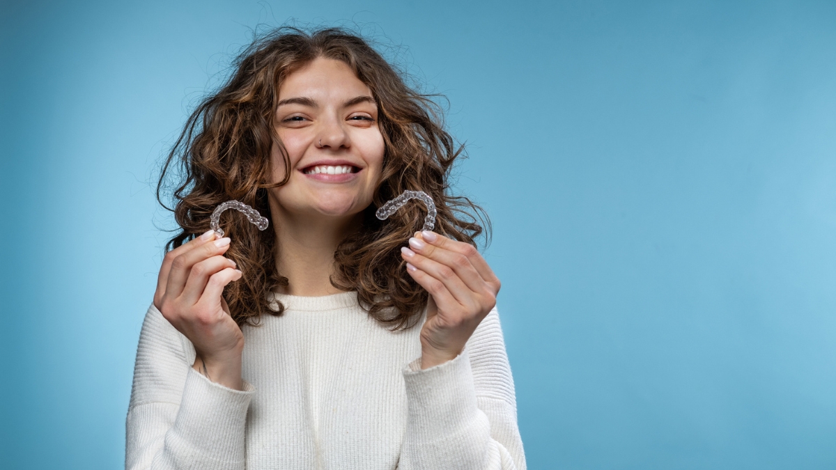 a woman holding a pair of invisible braces from NewSmile Aligners