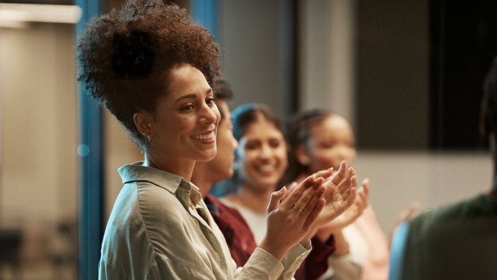 Smiling business colleagues clapping and applauding during meeting in board room at office