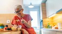 an older woman with short hair and glasses eating a health salad with lots of veggies