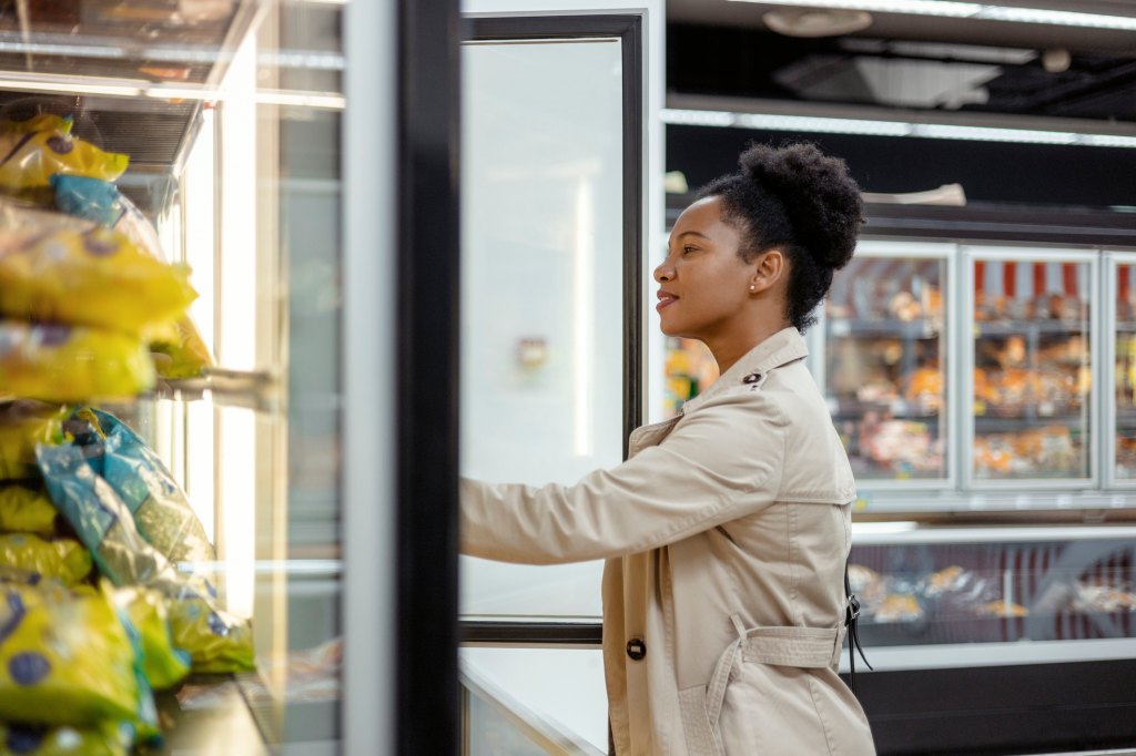 woman shopping in the freezer aisle at grocery store
