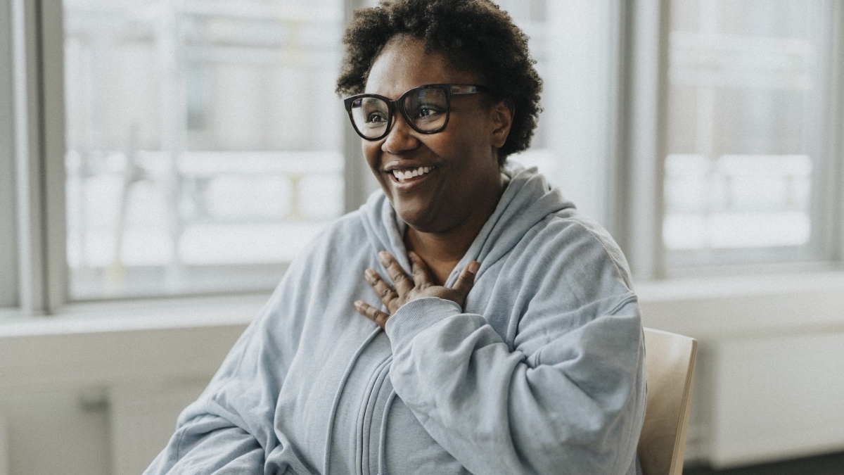 A woman holding her hand to her to chest while breathing slowly to ease angina symptoms