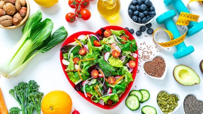 Heart-shaped plate of salad greens surrounded by vegetables