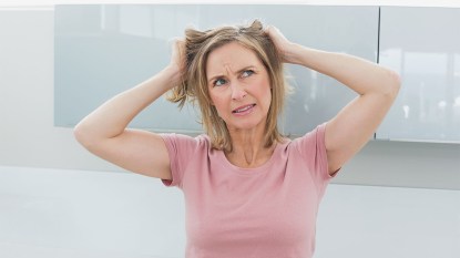 woman touching her head wondering what that smell on her scalp is