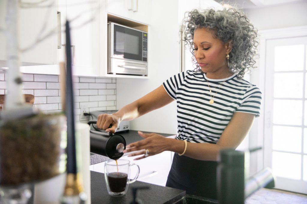 mature woman making coffee with the new Dunkin' mint chip coffee grounds