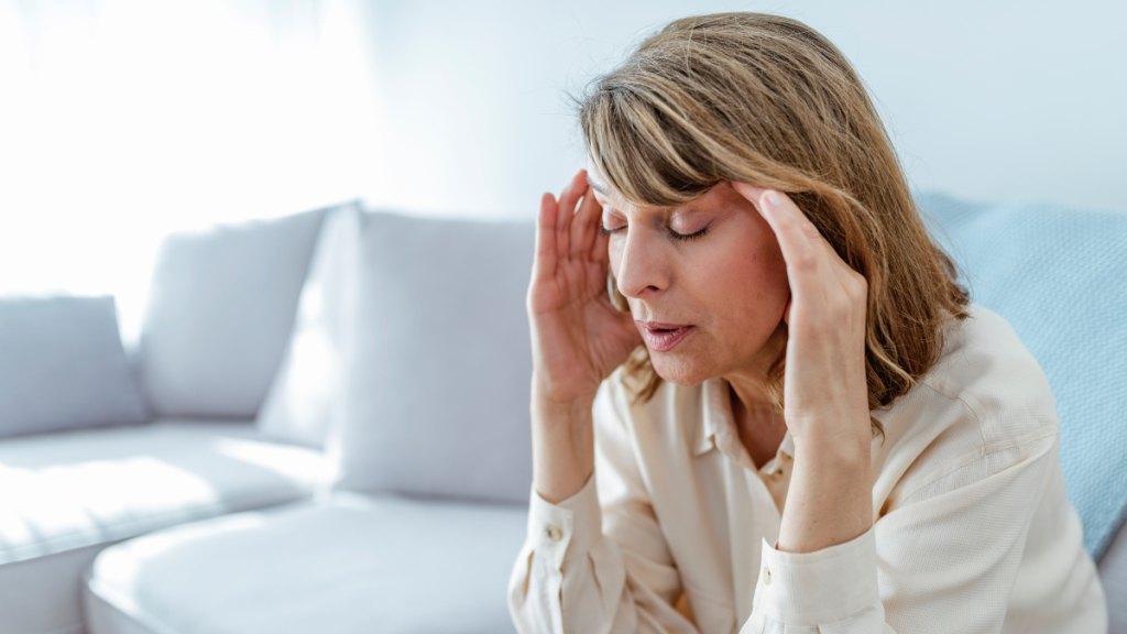 A woman holding her hands to her head while closing her eyes due to elevated cortisol