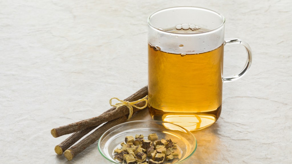 A mug of licorice root herbal brew beside fresh licorice