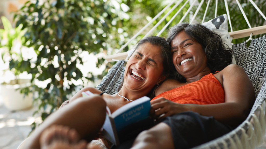 A mother and daughter lying in a hammock together laughing to reduce cortisol