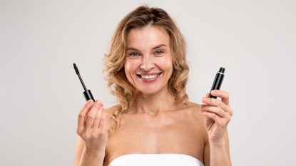 mature woman smiling holding mascara tube for mascara cocktailing
