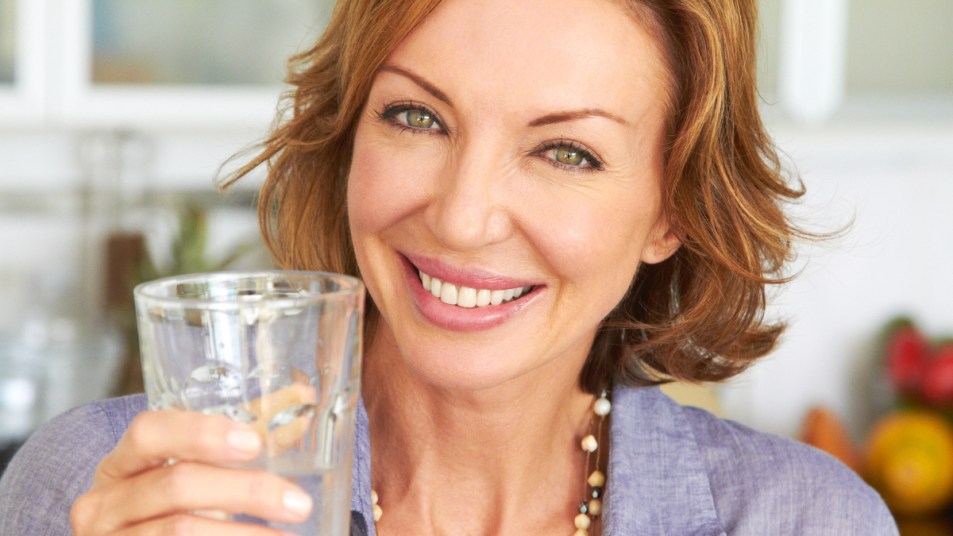 A woman with short hair holding a glass of water with Epsom salt for constipation