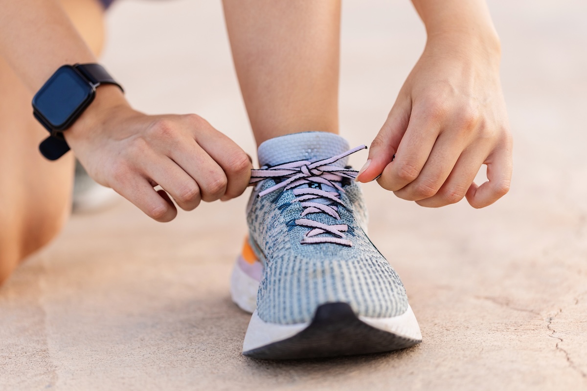 Close-up view of female jogger hands tying laces of her sport shoes before running exercise routine
