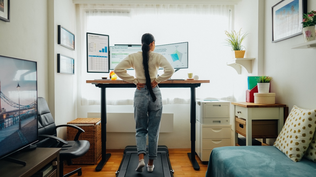 Woman working at standing desk and walking pad in her home office.