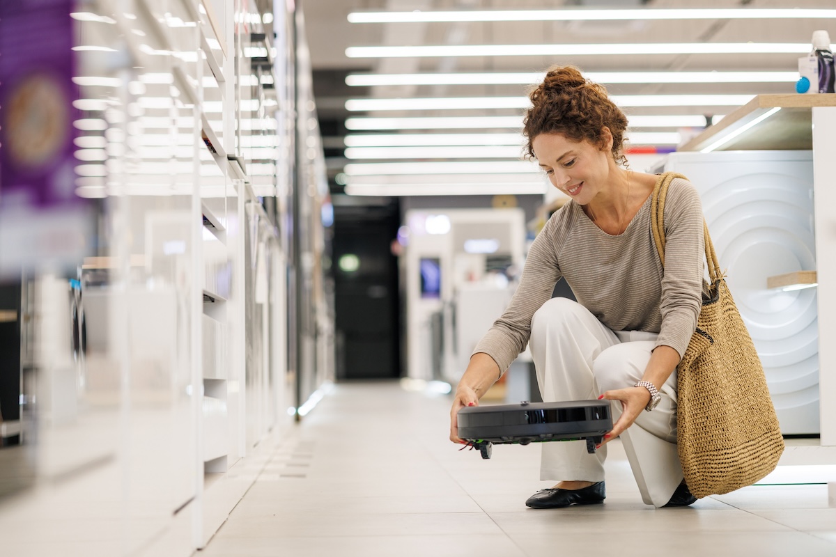 Mid-adult woman testing a high-tech robot vacuum in store