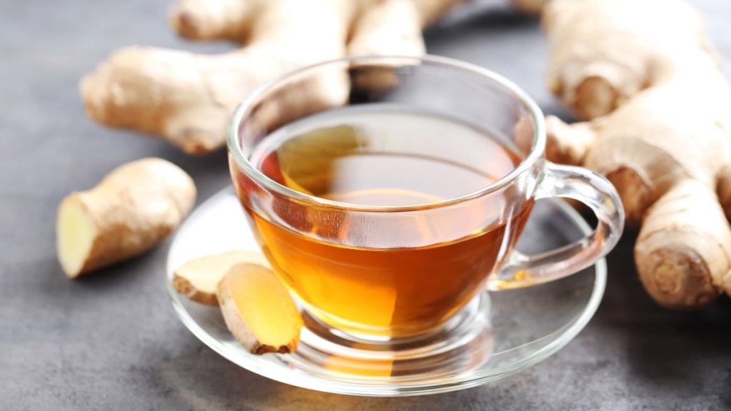 A cup of ginger tea beside fresh ginger root