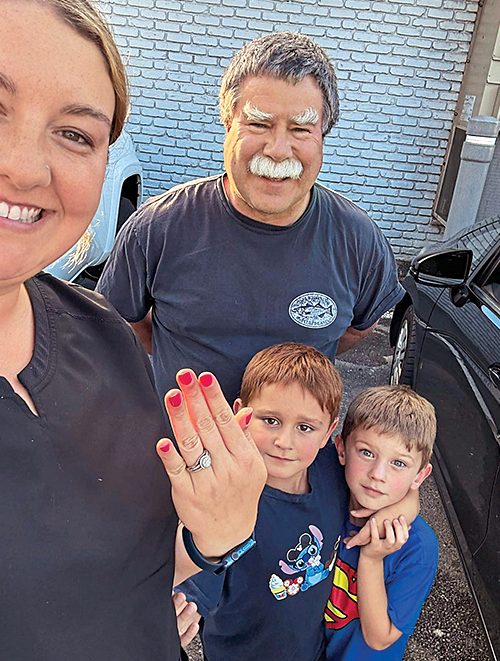 Woman with her sons holding up her hand with a ring.