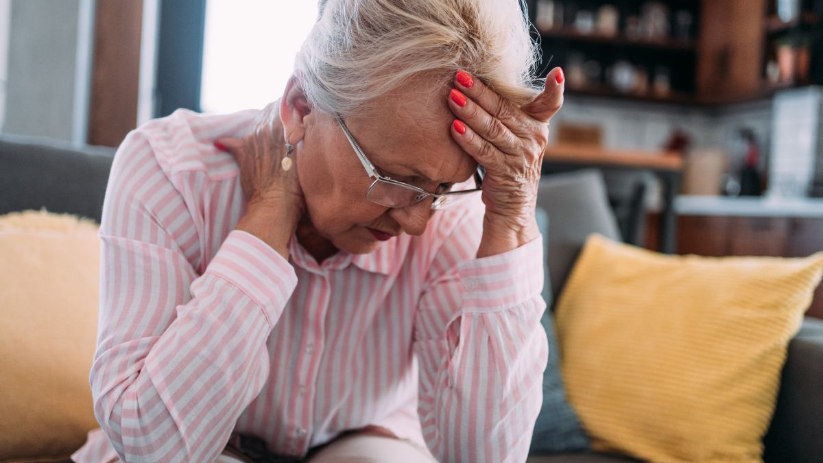 woman holding her head closing her eyes having headache, dizziness, trouble seeing, symptoms of potential blocked artery in neck