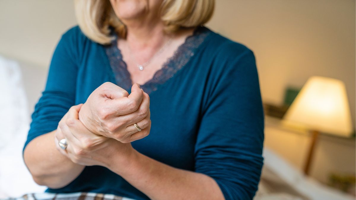 closeup of woman holding her wrist in pain, which can be a symptom of gout