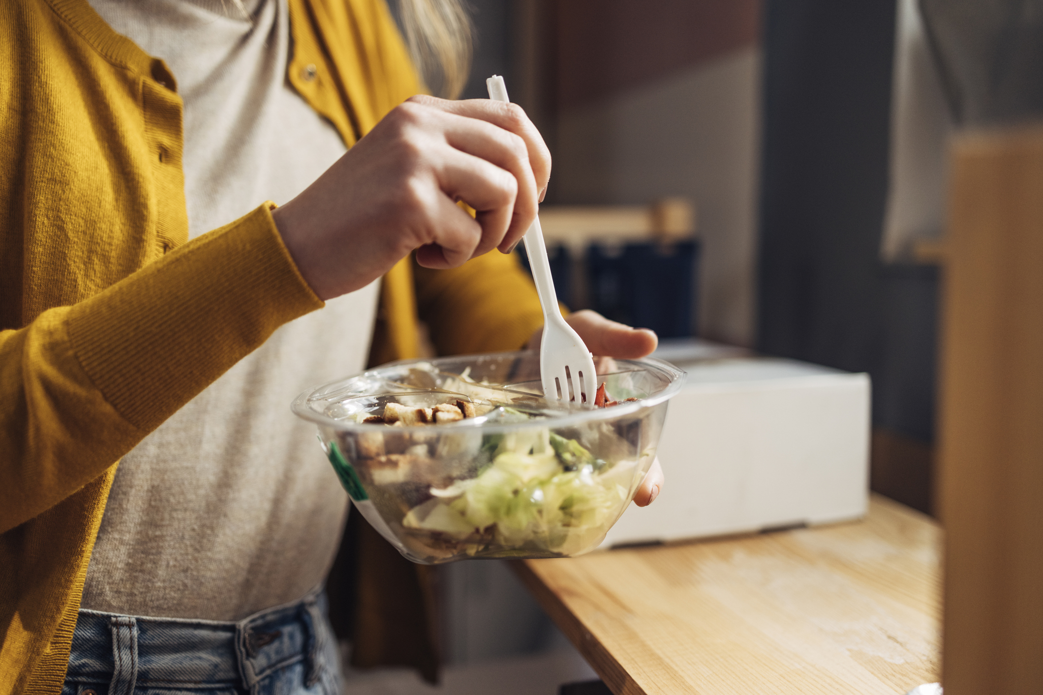 mature woman eating a salad kit out of plastic container