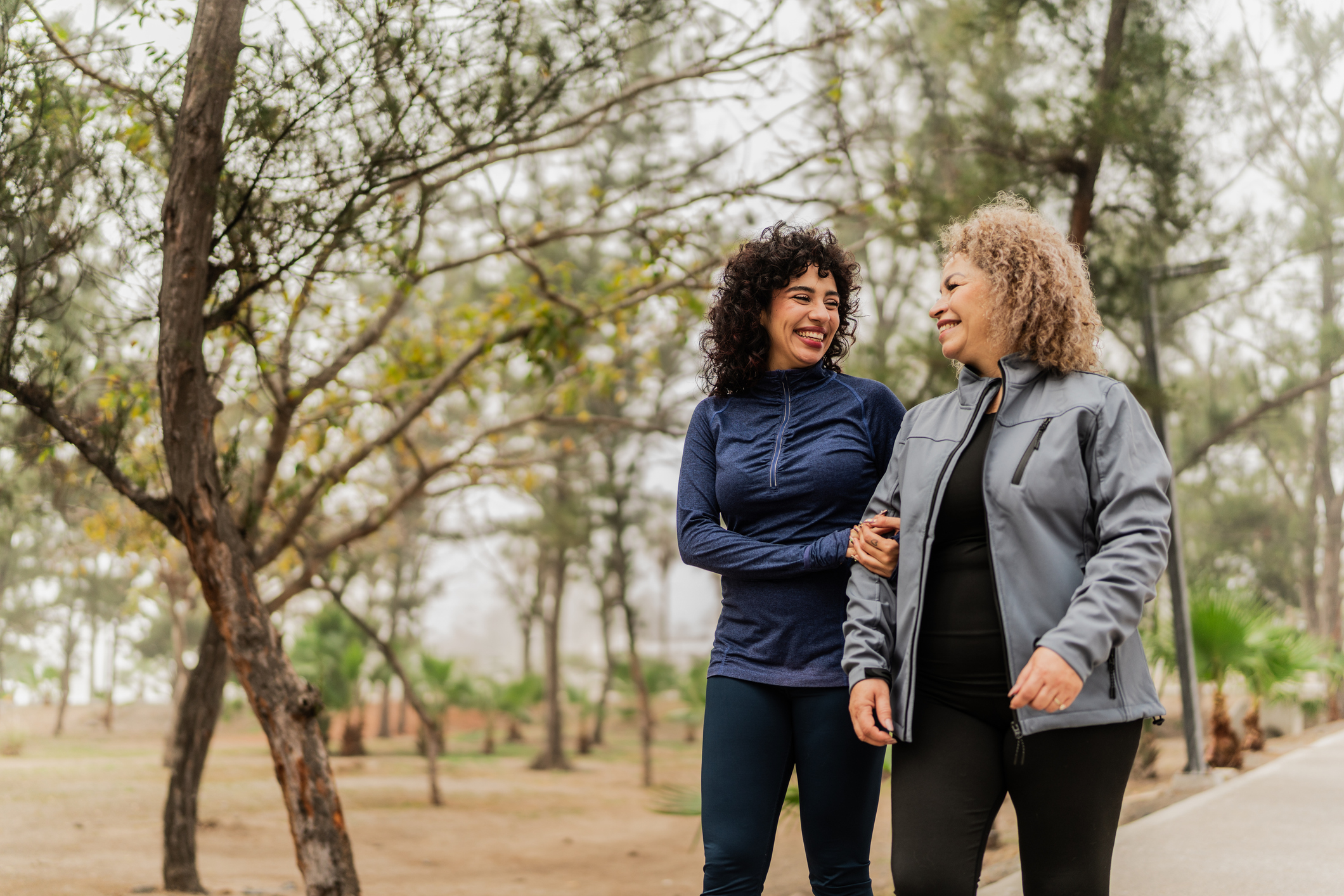 two mature women practicing wellness walks outside in woods